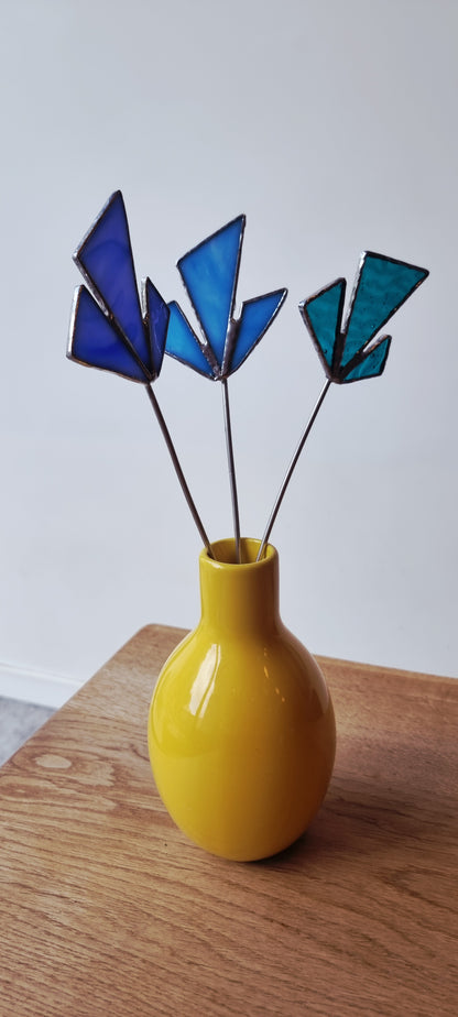 Handgemaakte glas in lood bloemen in blauwe tinten in een gele vaas op houten tafel, Maak Atelier