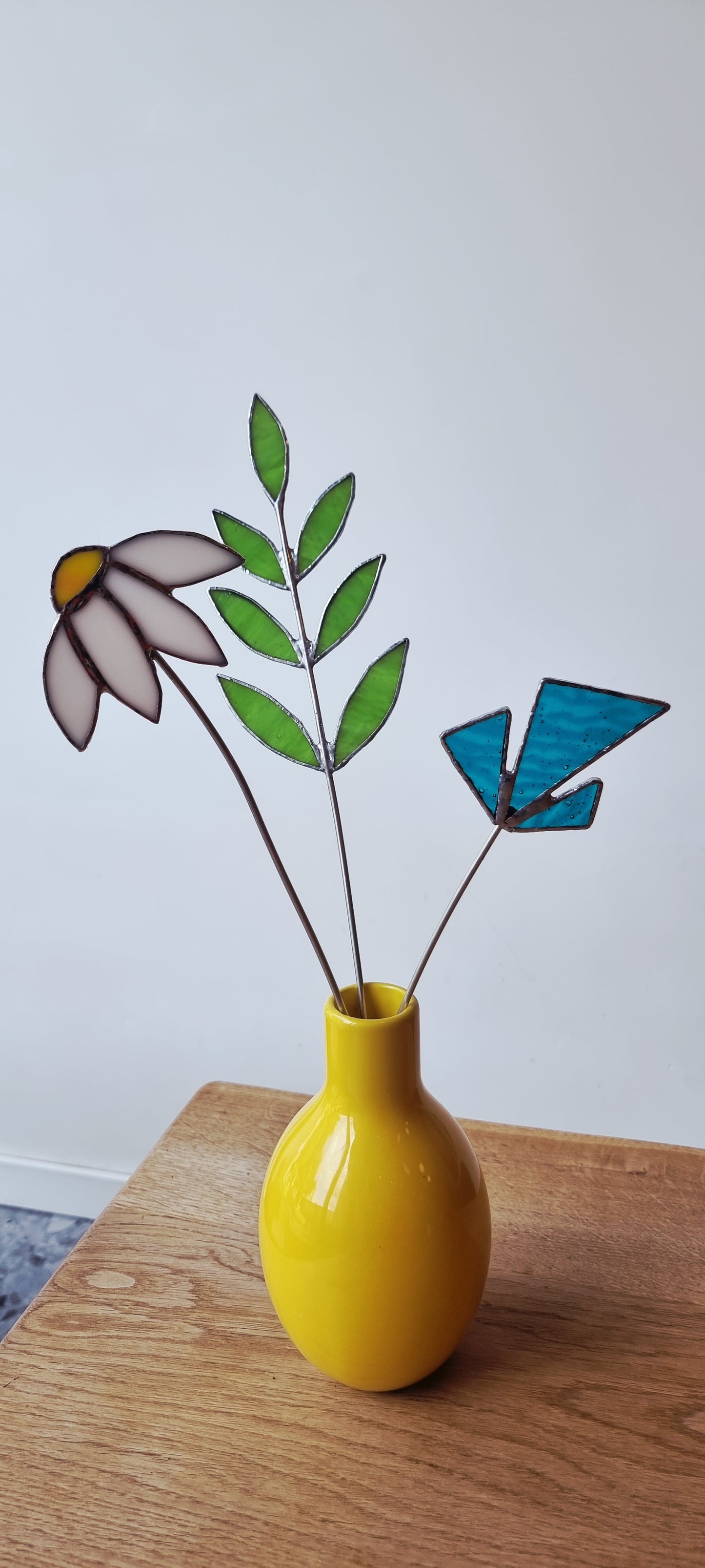 Handgemaakte glas in lood bloemen in gele vaas, op houten tafel, Maak Atelier Antwerpen.