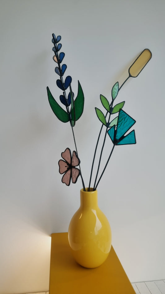 Handgemaakte glas in lood bloemen in een gele vaas op tafel bij Maak Atelier Antwerpen workshop