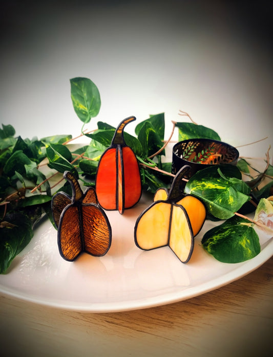 Handgemaakte glas in lood pompoenen decoratie op een bord met groene bladeren, Maak Atelier Antwerpen